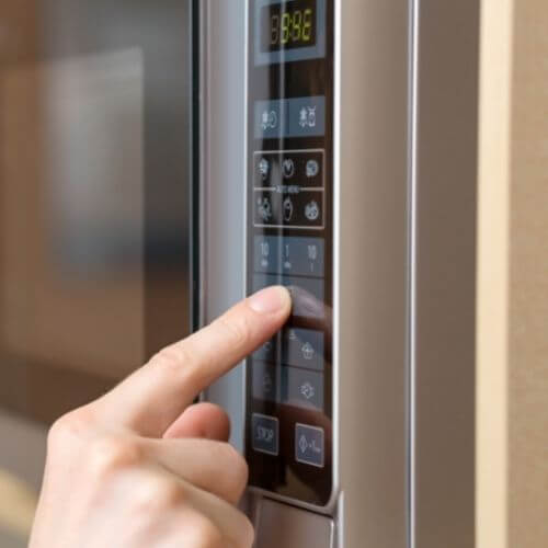 Image of a person pushing an option on microwave keypad