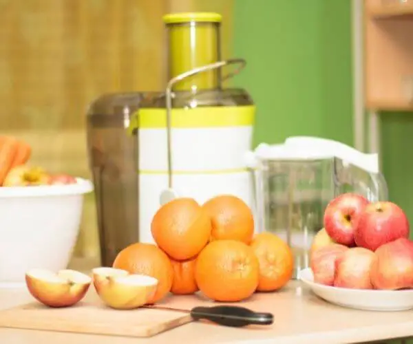juicer next to fruit and a cutting board with knife