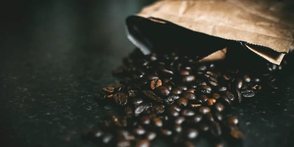 coffee beans spilling out of bag. flavor is reason that french presses produce better coffee than Keurig machines.