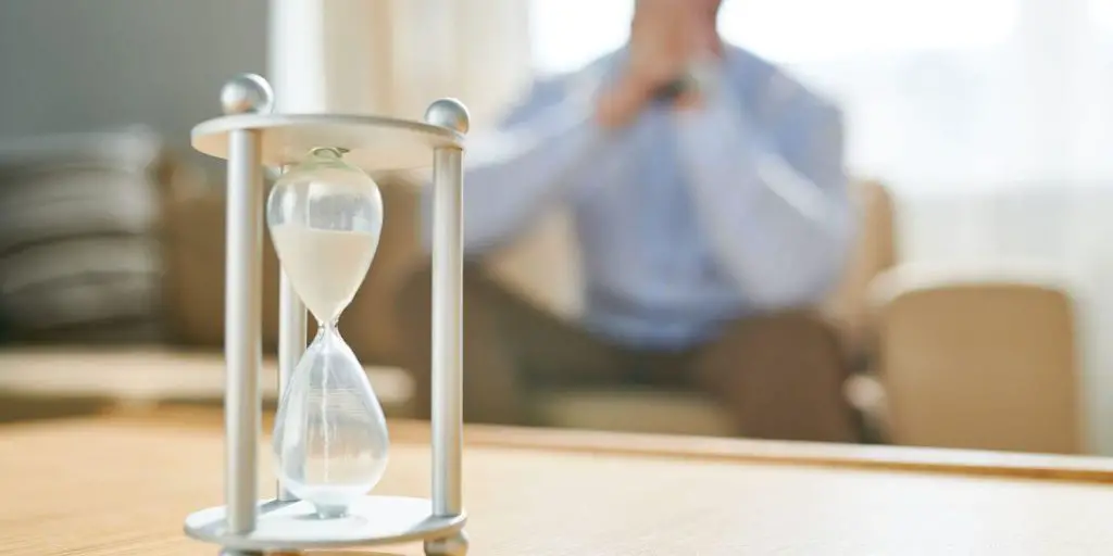 image of man watching hour glass. 