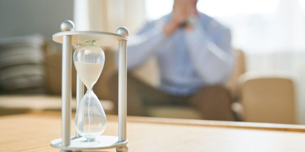 image of man watching hour glass. 