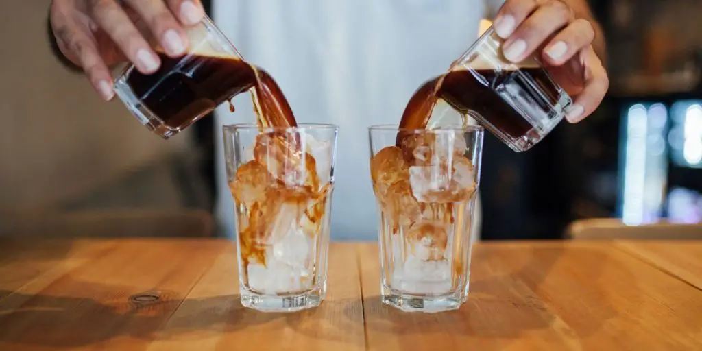 person pouring iced coffee