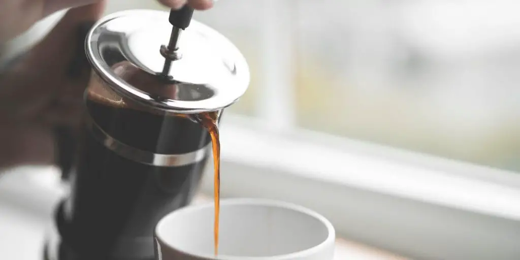 image of person pouring french press coffee in to mug. 