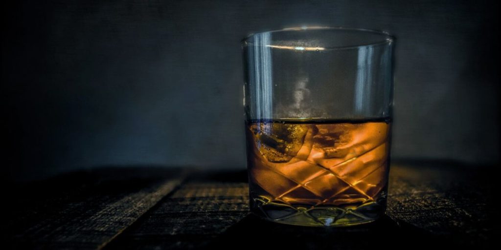 a glass of bourbon with dark background