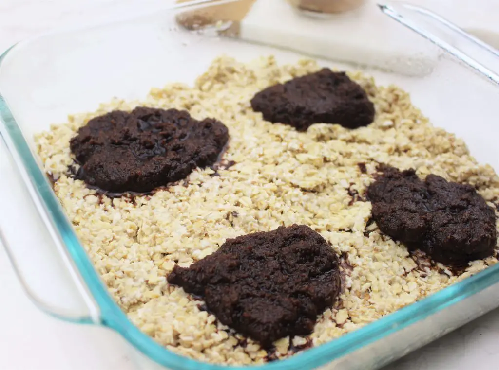 scooping cinnamon roll filling onto oatmeal mixture